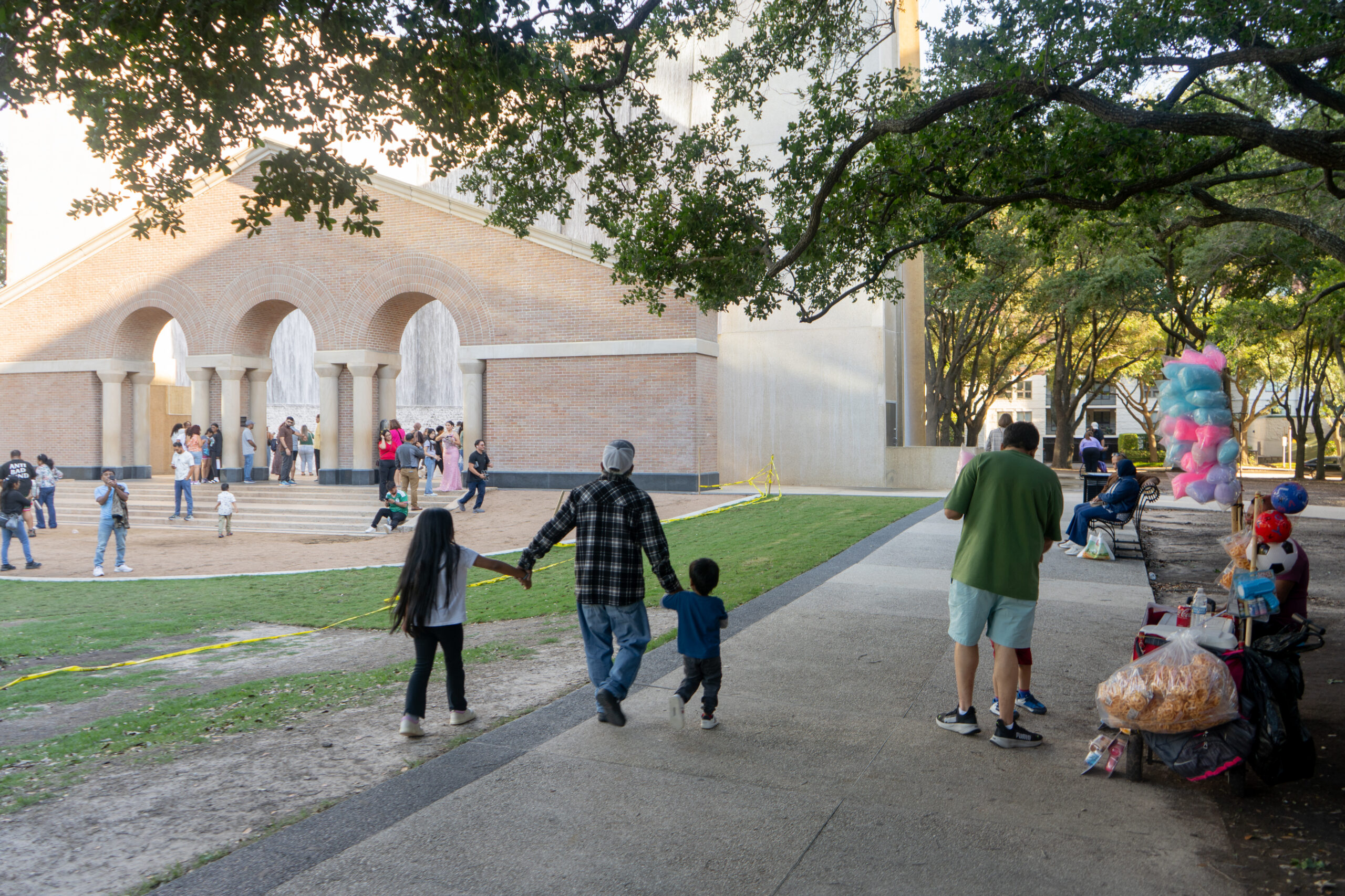 Family walking along the sidewalk with the Hines Waterwall in the Background.